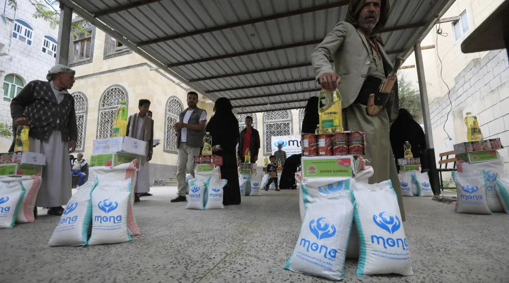 يمنيون يقفون بجوار حصصهم من المساعدات الغذائية وسط أزمة في الأمن الغذائي... في صنعاء، اليمن 7 مايو 2025 (إ.ب.أ)